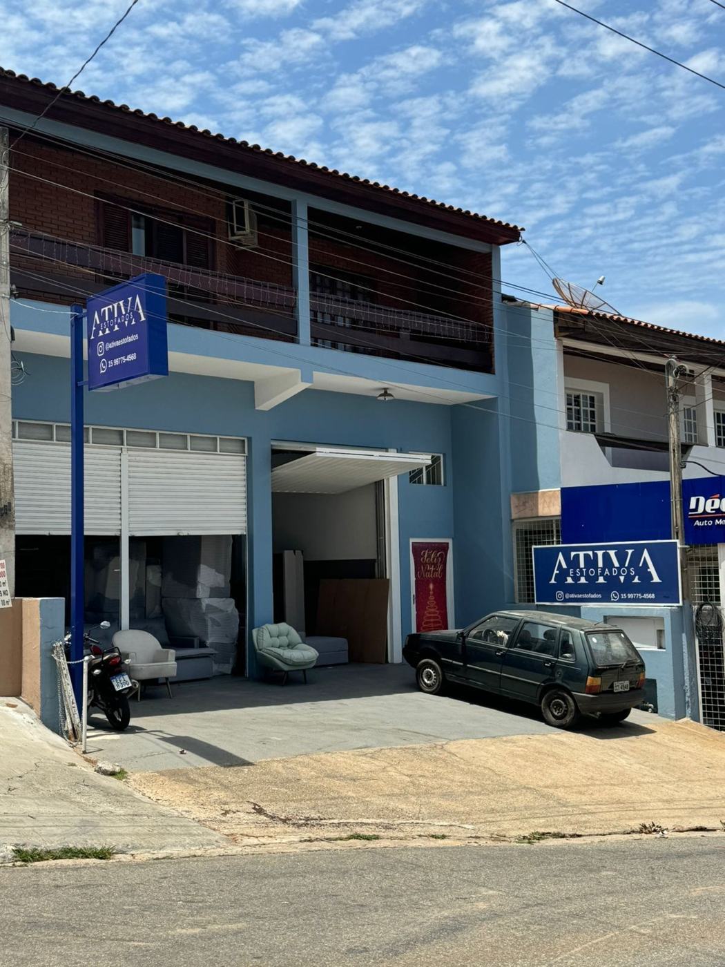 Fachada azul da Ativa Estofados com placas da loja e sofás na entrada