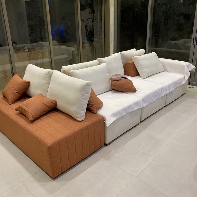 Sofá modular branco com módulo caramelo e almofadas, em sala ampla